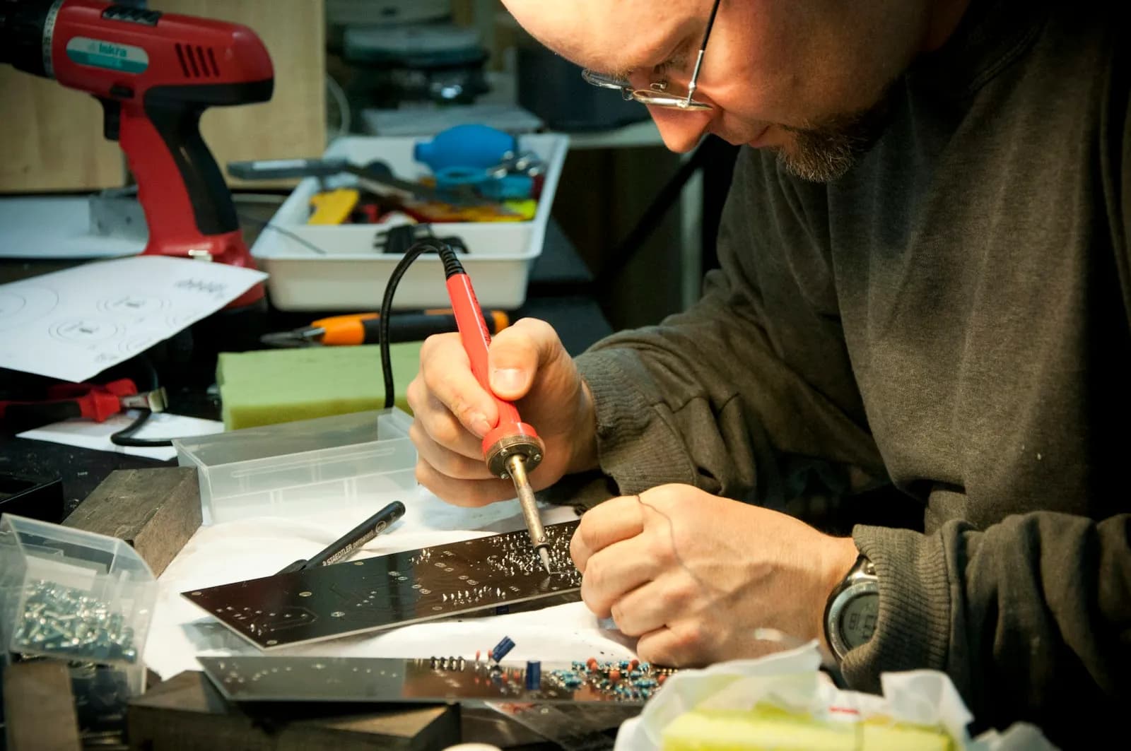 Tecnico che salda una scheda elettronica al banco di un laboratorio